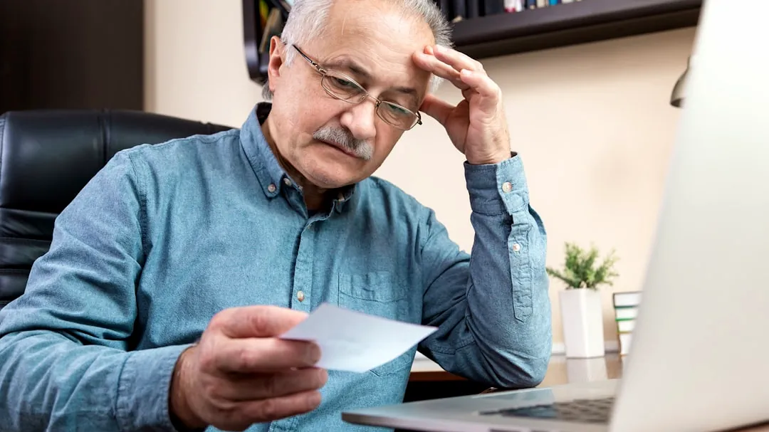 a man holding a pen and looking at a laptop