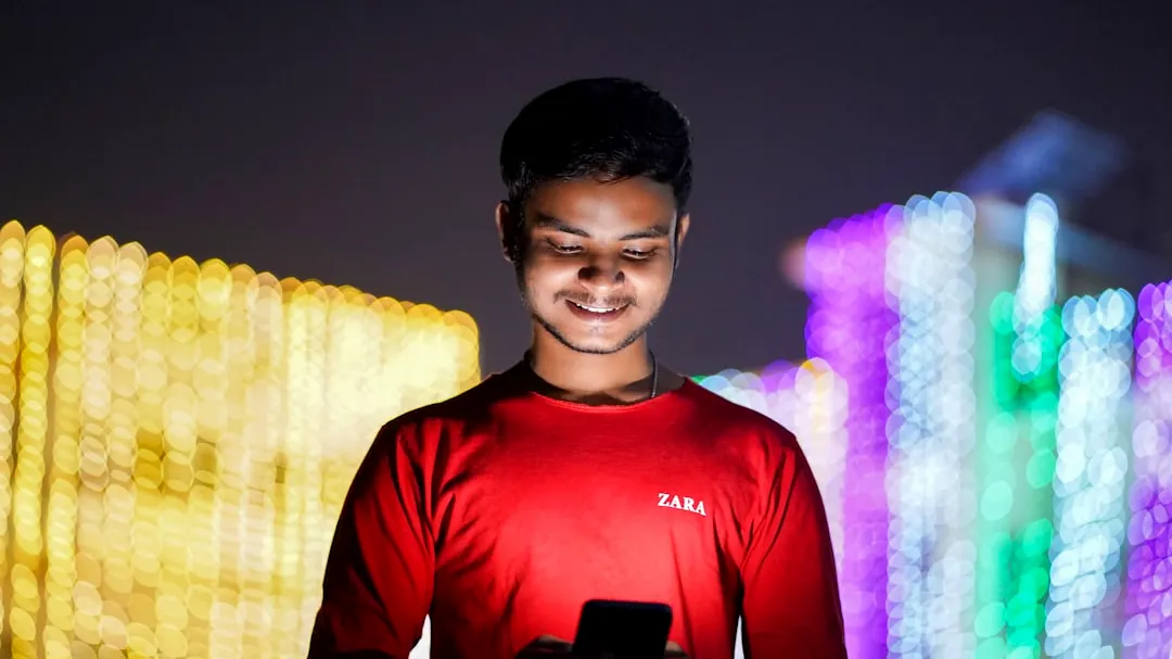 A man standing in front of a wall with a cell phone