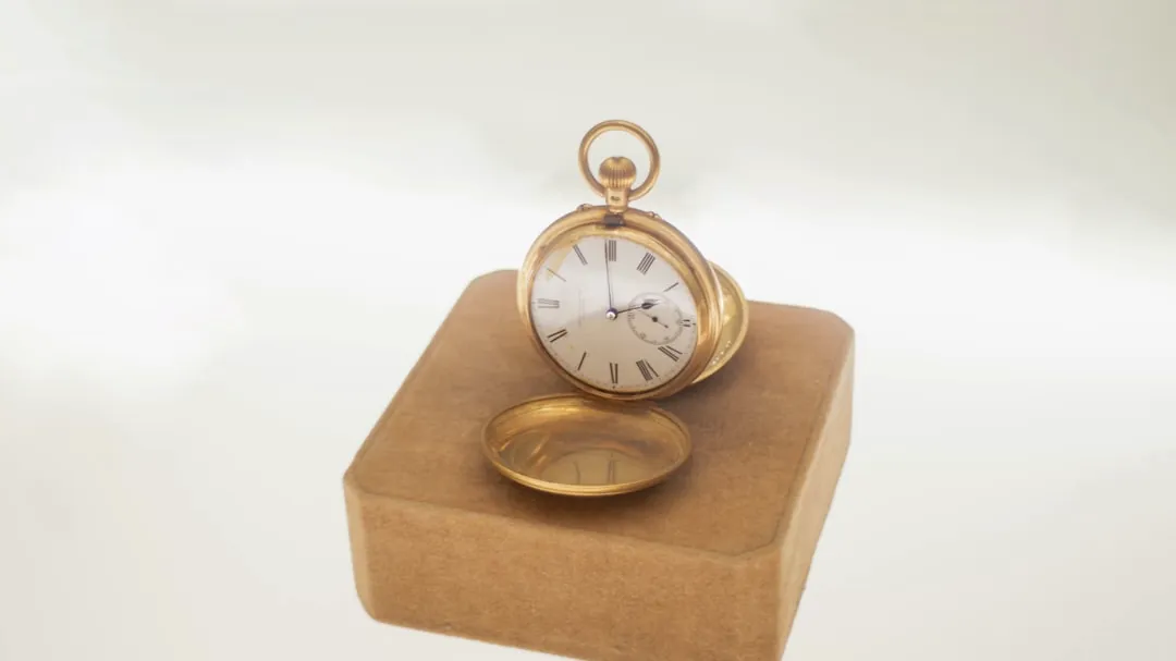 Antique gold pocket watch on display stand