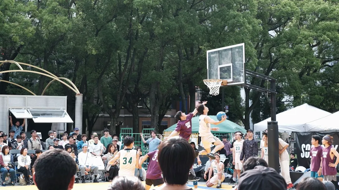Basketball players competing in an outdoor game with spectators watching