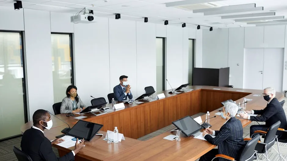 Business professionals wearing masks attending a conference meeting in a modern setting.