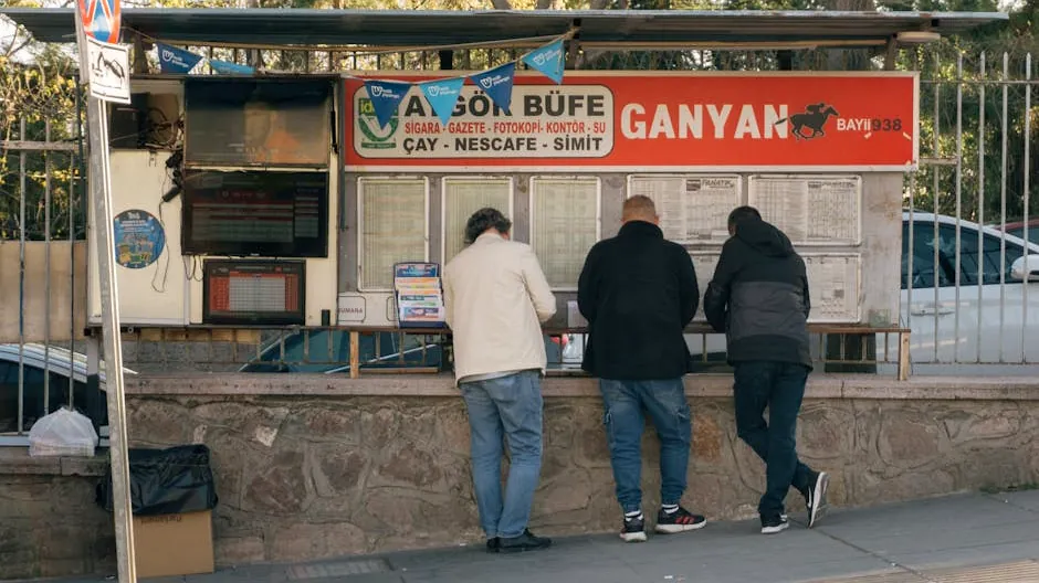 Three men at a street kiosk in Turkey, checking sports betting results on a sunny day.