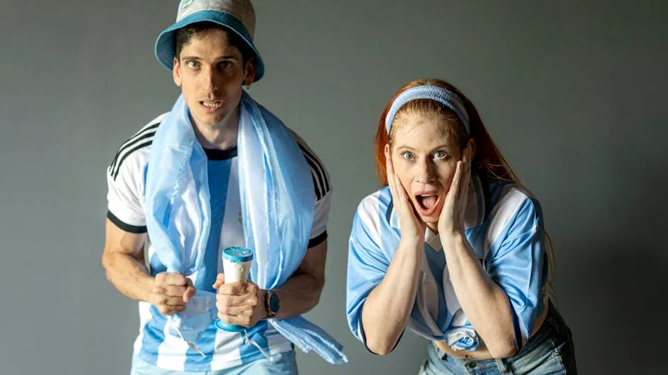 Two passionate Argentine fans celebrating with excitement, wearing team colors indoors.