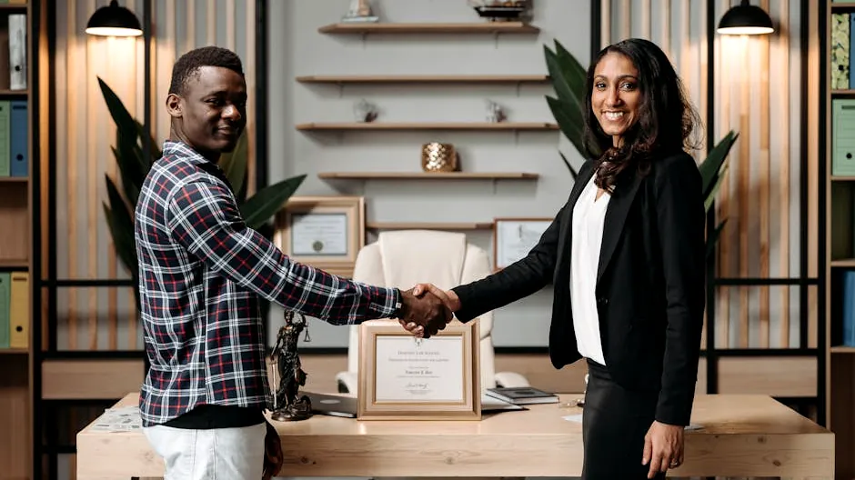 Two professionals shaking hands in an office setting, symbolizing business agreement.