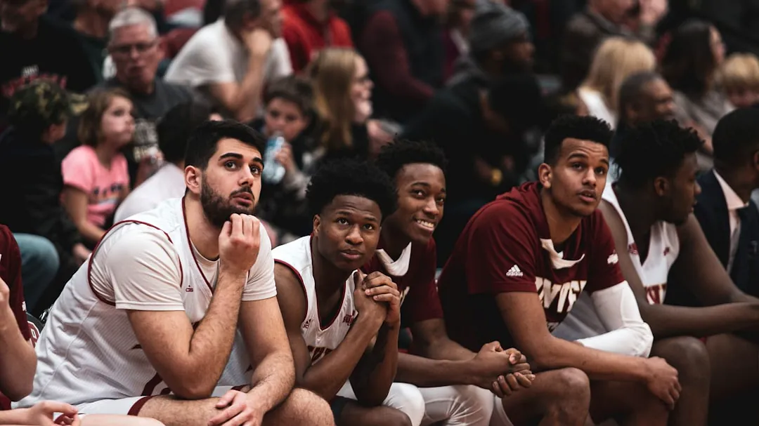 a group of young men sitting on top of a basketball court