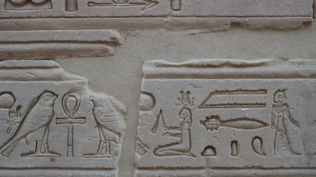 Ancient egyptian hieroglyphs carved into stone wall