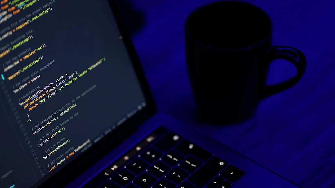 black laptop computer turned on beside black ceramic mug