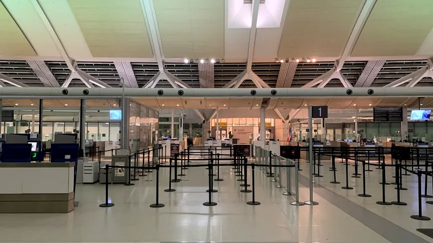 Empty check-in area of a modern airport with sleek design and organized layout.