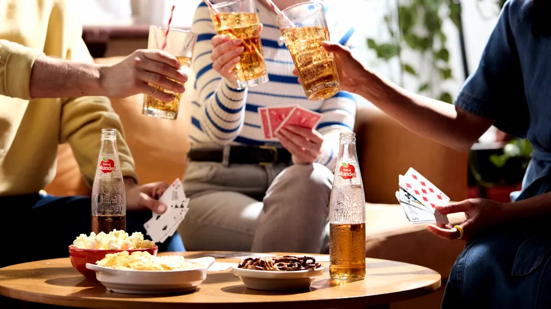 Friends are playing cards and enjoying drinks together.