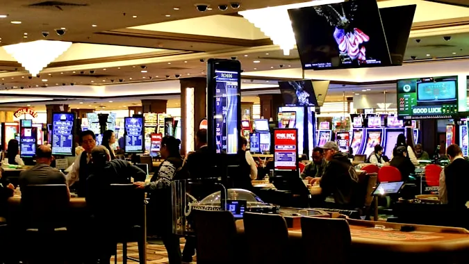 People playing slot machines in a brightly lit casino.