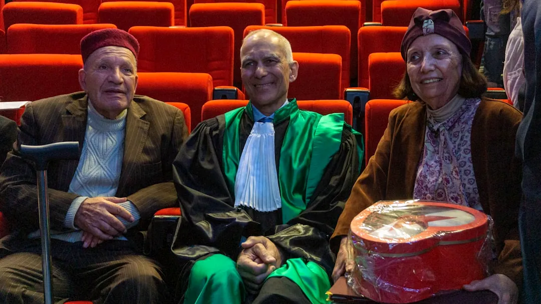 Three people in an auditorium with red seats